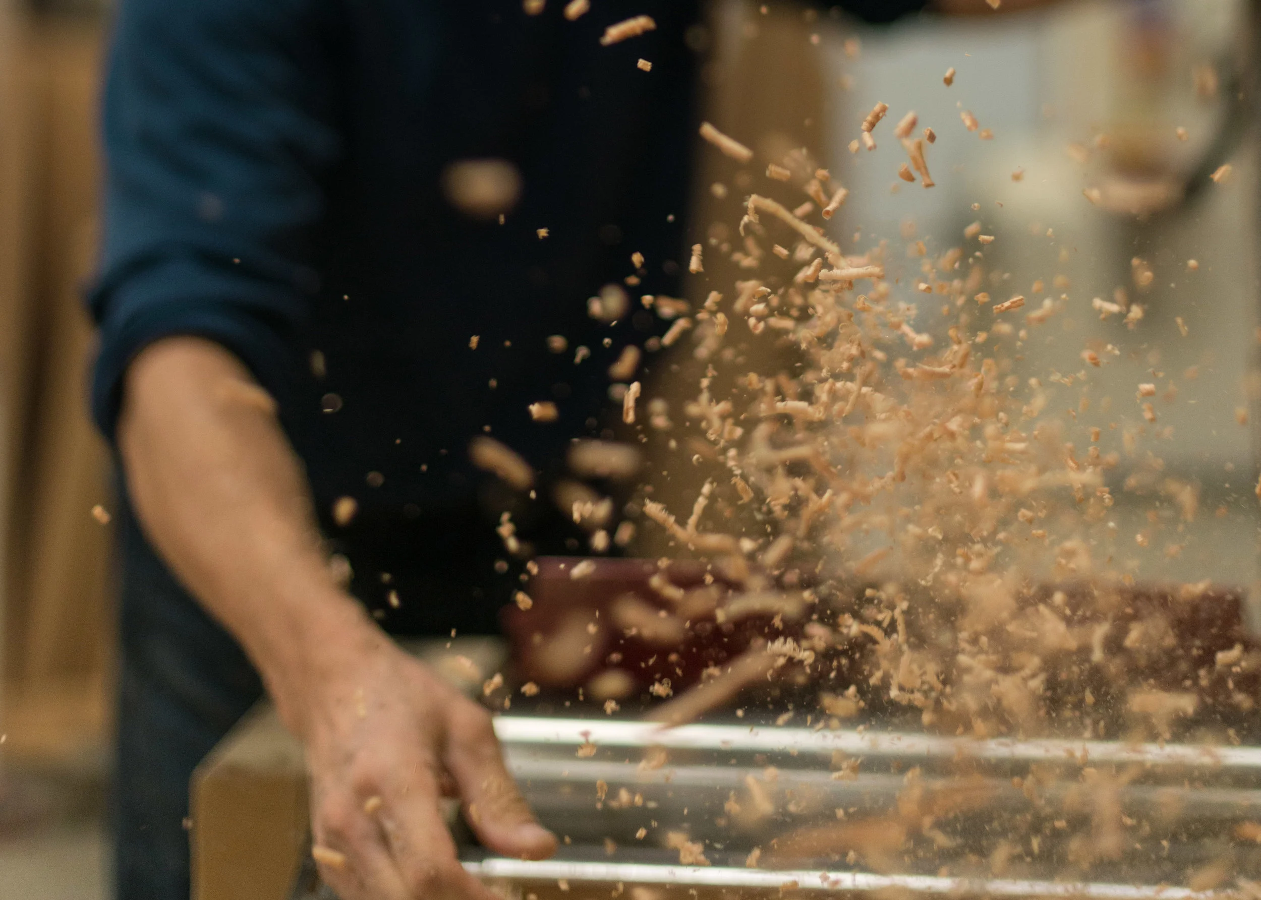 Wood shavings flying from a machine in the Vega Kitchens workshop